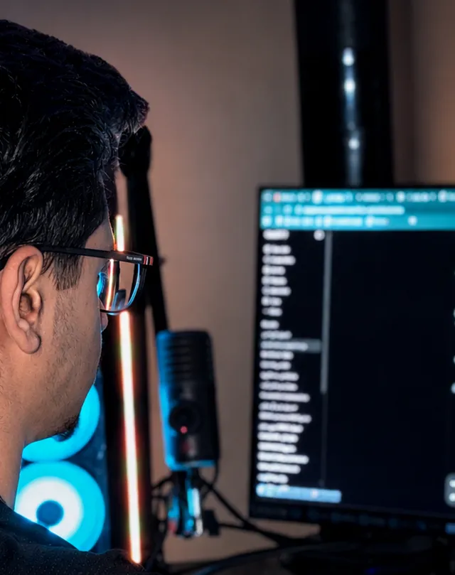 Alex focused at his workstation, seen from behind in low cinematic light